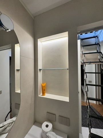 Bagno con pareti chiare e nicchie illuminate
